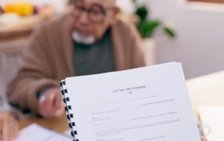 Hand holding a Last Will and Testament with elderly man in background, illustrating power of attorney and guardianship legal planning in New Jersey