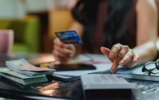 Person with calculator and credit card illustrating how Chapter 13 bankruptcy handles credit card debt.