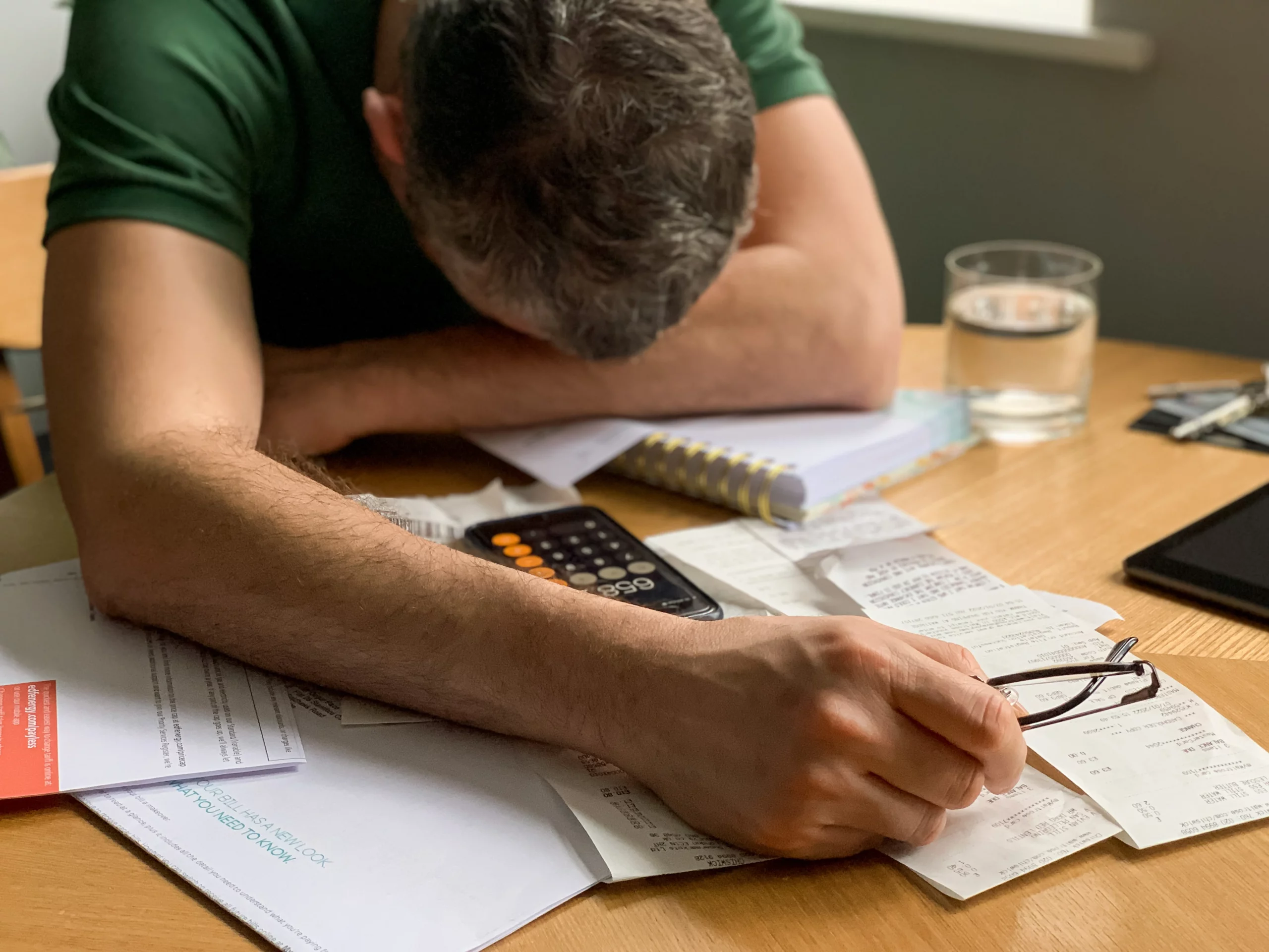 Person overwhelmed with bills and calculator illustrating nondischargeable debts in New Jersey bankruptcy.